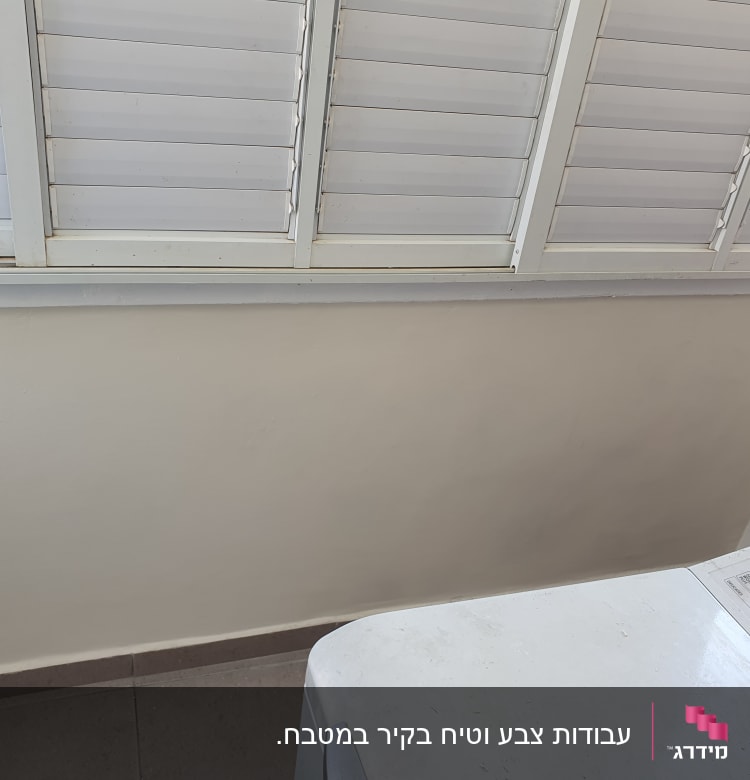 קיר צבוע בלבן עם חלון תריסים